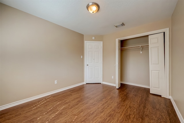 unfurnished bedroom with a closet and dark hardwood / wood-style flooring