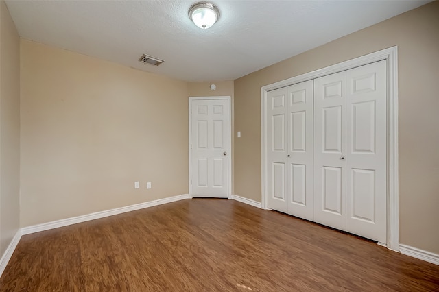 unfurnished bedroom with hardwood / wood-style floors, a textured ceiling, and a closet