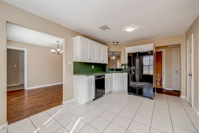 kitchen with black appliances, sink, ceiling fan with notable chandelier, white cabinetry, and light hardwood / wood-style flooring