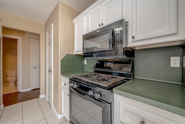 kitchen with a textured ceiling, black appliances, light tile patterned flooring, and white cabinets