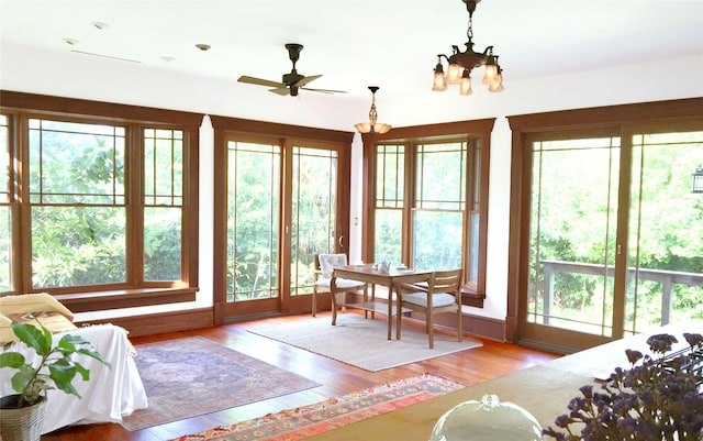 sunroom with ceiling fan with notable chandelier and a wealth of natural light