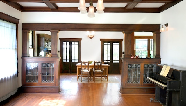 dining space with beam ceiling, hardwood / wood-style flooring, decorative columns, and plenty of natural light