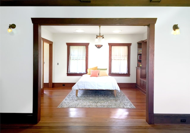 bedroom with a notable chandelier, multiple windows, and wood-type flooring