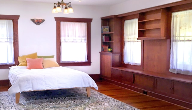 bedroom with multiple windows, a chandelier, and dark hardwood / wood-style floors