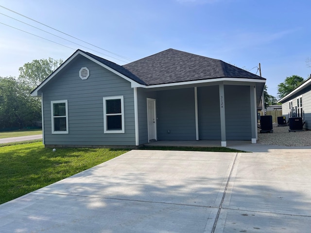 ranch-style home featuring roof with shingles, a porch, central AC, and a front yard