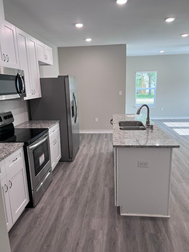 kitchen with a sink, appliances with stainless steel finishes, a kitchen island with sink, and white cabinetry