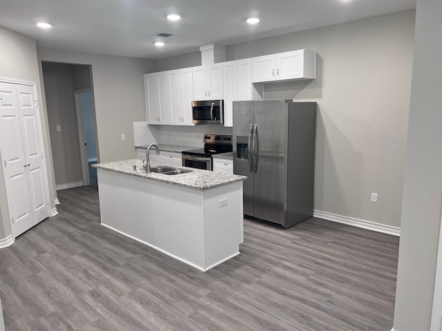 kitchen featuring light stone counters, white cabinets, sink, wood-type flooring, and appliances with stainless steel finishes