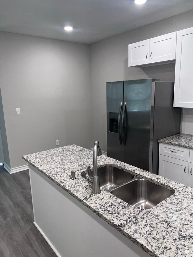 kitchen featuring white cabinetry, light stone countertops, dark hardwood / wood-style flooring, sink, and stainless steel fridge with ice dispenser