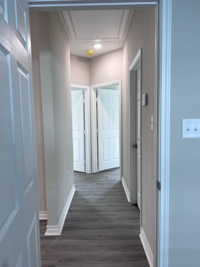 corridor featuring baseboards, attic access, and dark wood-style flooring