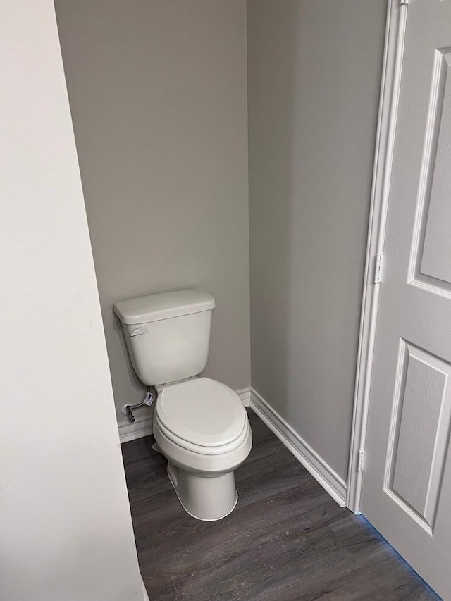 bathroom with baseboards, wood finished floors, and toilet