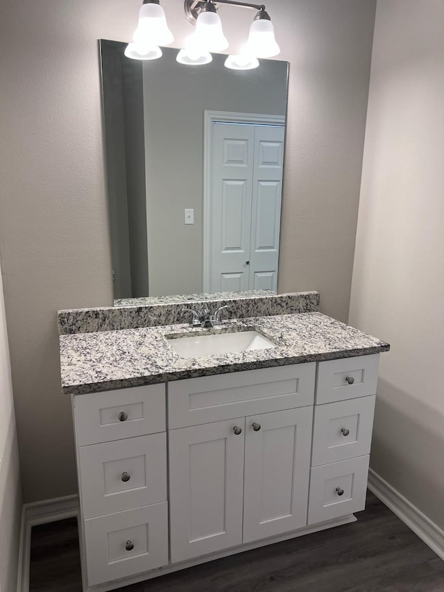 bathroom with baseboards, wood finished floors, and vanity