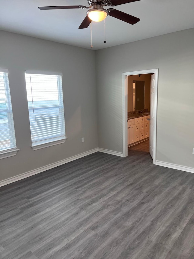 unfurnished room with baseboards, ceiling fan, and dark wood finished floors