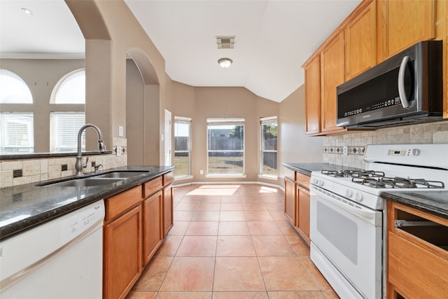 kitchen featuring a healthy amount of sunlight, decorative backsplash, white appliances, and light tile patterned floors