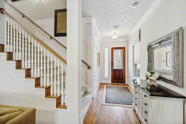 entrance foyer featuring a textured ceiling, light hardwood / wood-style floors, and ornamental molding