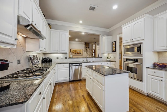 kitchen with white cabinets, a center island, stainless steel appliances, and light hardwood / wood-style flooring