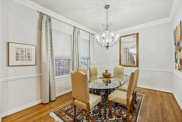 dining space with wood-type flooring, ornamental molding, and an inviting chandelier