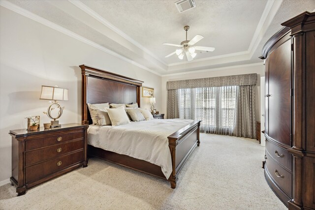 bedroom featuring light carpet, a textured ceiling, a raised ceiling, ceiling fan, and crown molding