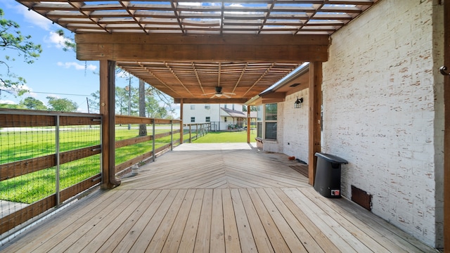 deck featuring ceiling fan, a lawn, and a pergola