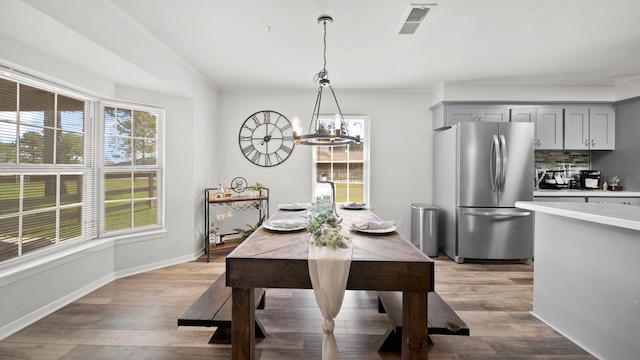 dining area with a notable chandelier, ornamental molding, and light wood-type flooring