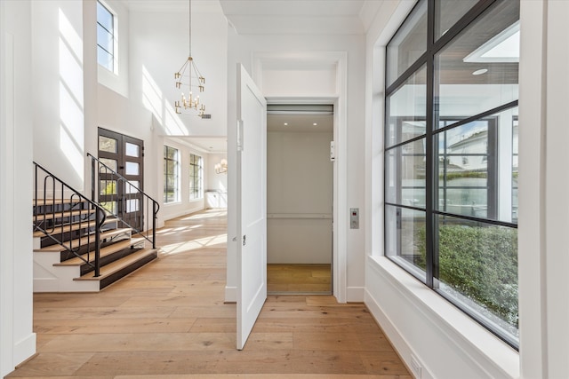 entryway featuring light wood-type flooring, a notable chandelier, and a wealth of natural light