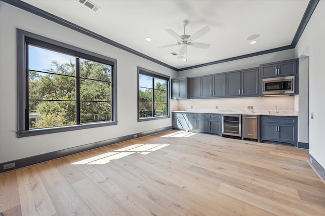 kitchen with stainless steel microwave, crown molding, sink, and light wood-type flooring