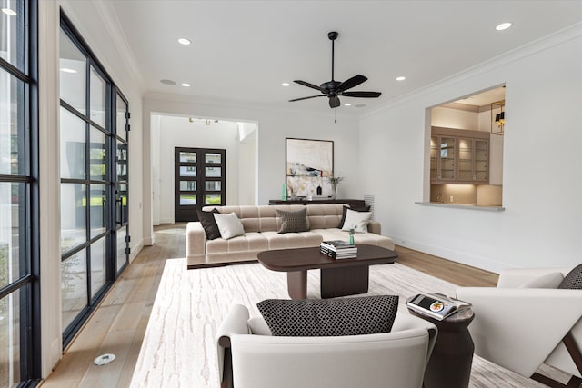 living room with french doors, light wood-type flooring, ornamental molding, and ceiling fan