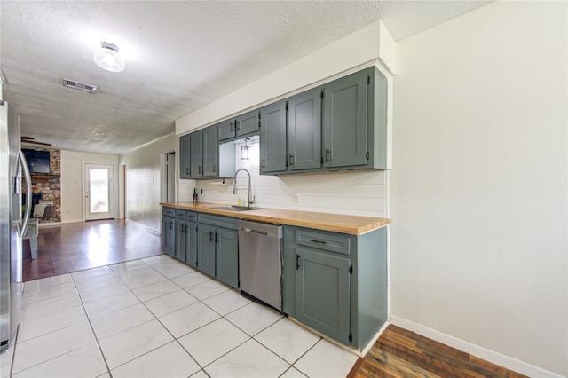 kitchen featuring sink, butcher block countertops, a textured ceiling, stainless steel appliances, and light hardwood / wood-style flooring