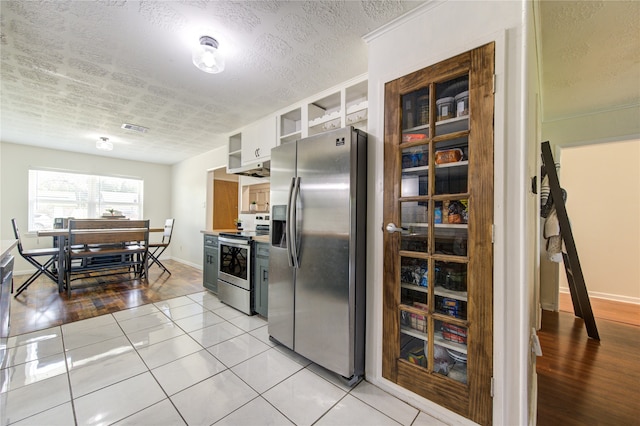 kitchen with a textured ceiling, appliances with stainless steel finishes, light hardwood / wood-style flooring, and white cabinets