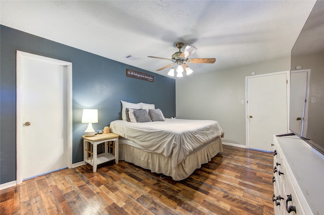 bedroom with dark wood-type flooring, ceiling fan, and a textured ceiling