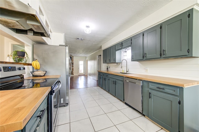 kitchen with sink, appliances with stainless steel finishes, a textured ceiling, and butcher block counters