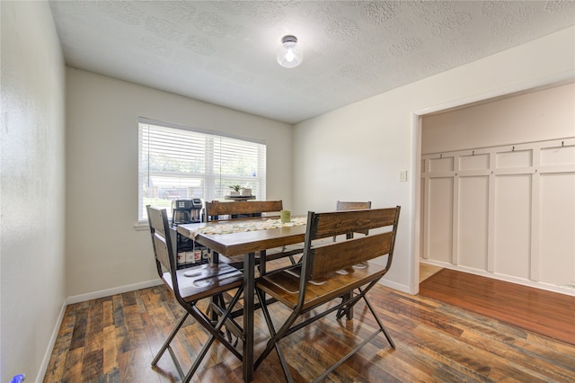 dining area with a textured ceiling and dark hardwood / wood-style flooring