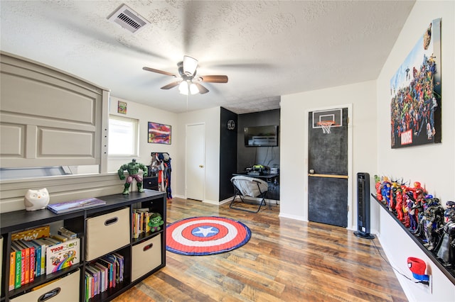 game room with a textured ceiling, ceiling fan, and dark hardwood / wood-style flooring