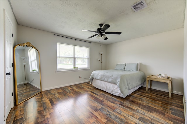 bedroom with ceiling fan, a textured ceiling, and dark hardwood / wood-style flooring