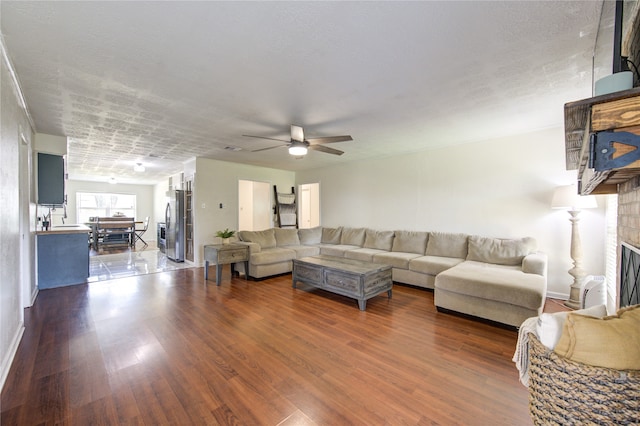 living room featuring dark wood-type flooring, sink, a textured ceiling, a fireplace, and ceiling fan