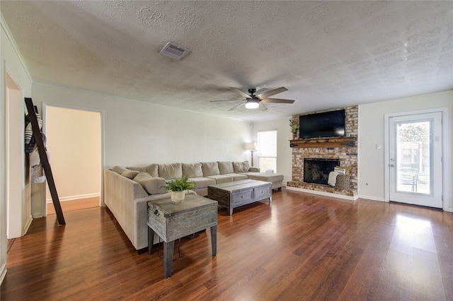 living room featuring a textured ceiling, a wealth of natural light, a fireplace, and dark hardwood / wood-style flooring