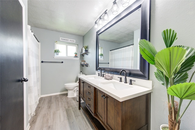 bathroom featuring a textured ceiling, walk in shower, wood-type flooring, toilet, and vanity