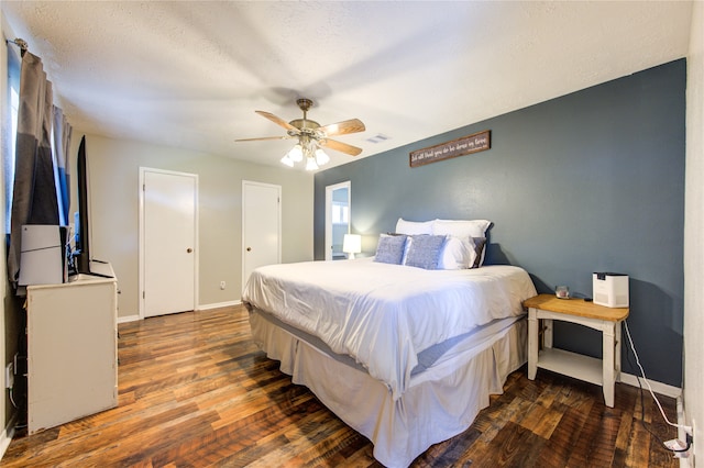 bedroom with a textured ceiling, dark hardwood / wood-style floors, and ceiling fan