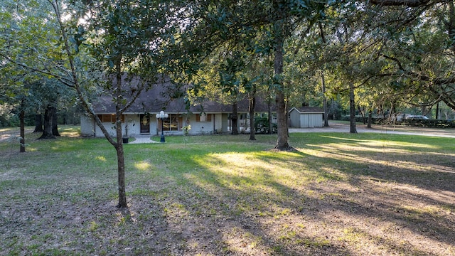 single story home with a storage unit and a front lawn