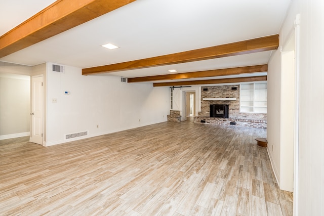 unfurnished living room with beam ceiling, light hardwood / wood-style flooring, and a brick fireplace