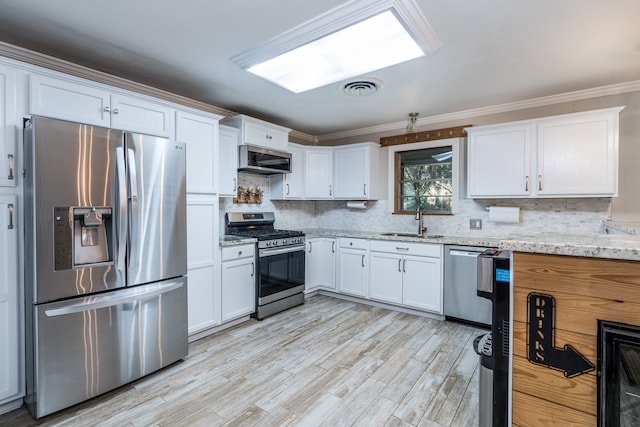 kitchen featuring white cabinets, appliances with stainless steel finishes, light hardwood / wood-style flooring, sink, and light stone counters