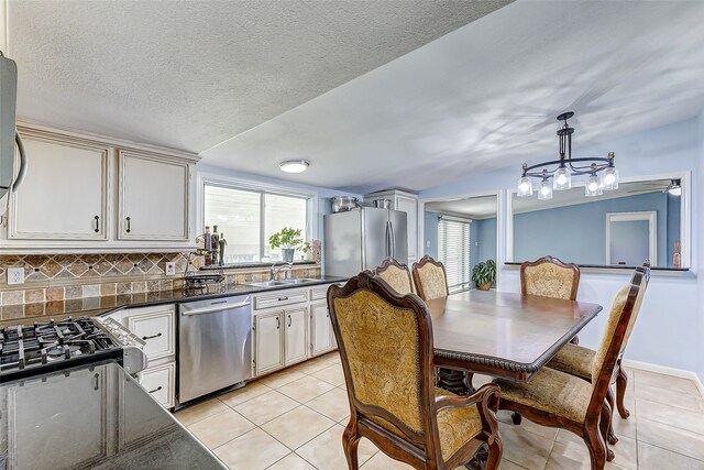 kitchen with tasteful backsplash, sink, hanging light fixtures, appliances with stainless steel finishes, and light tile patterned floors