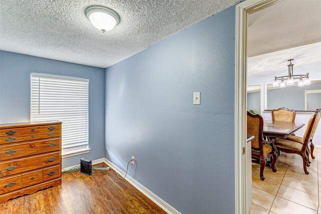 bedroom featuring a textured ceiling, light hardwood / wood-style flooring, and a notable chandelier