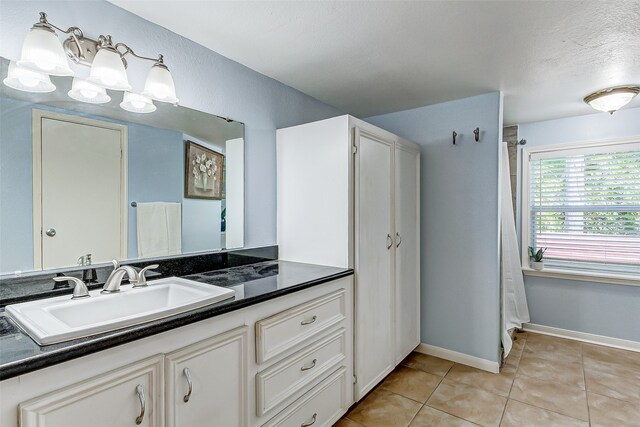 bathroom with a textured ceiling, vanity, curtained shower, and tile patterned floors