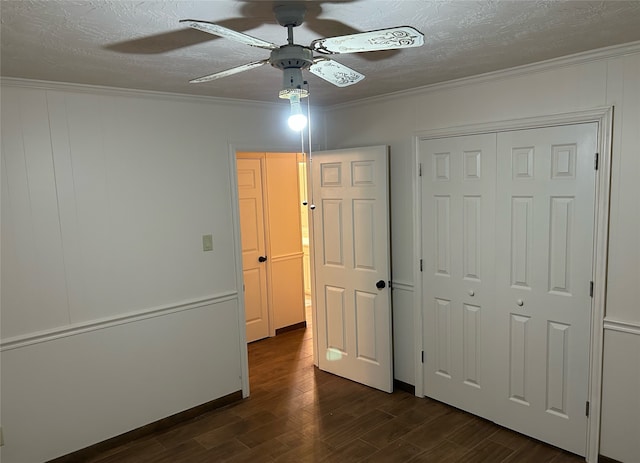 unfurnished bedroom featuring crown molding, ceiling fan, dark wood-type flooring, and a closet