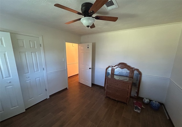 bedroom with ceiling fan, dark wood-type flooring, and a closet