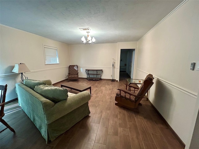 living room with a notable chandelier, crown molding, hardwood / wood-style floors, and a textured ceiling