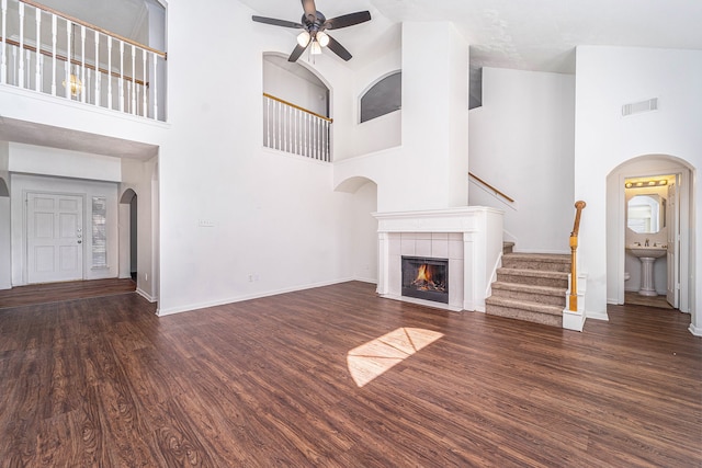 unfurnished living room with dark hardwood / wood-style floors, ceiling fan, a fireplace, and high vaulted ceiling