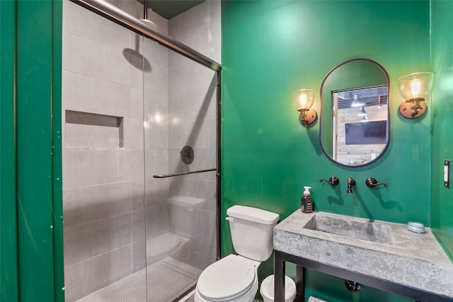 bathroom with toilet, sink, and a shower with shower door