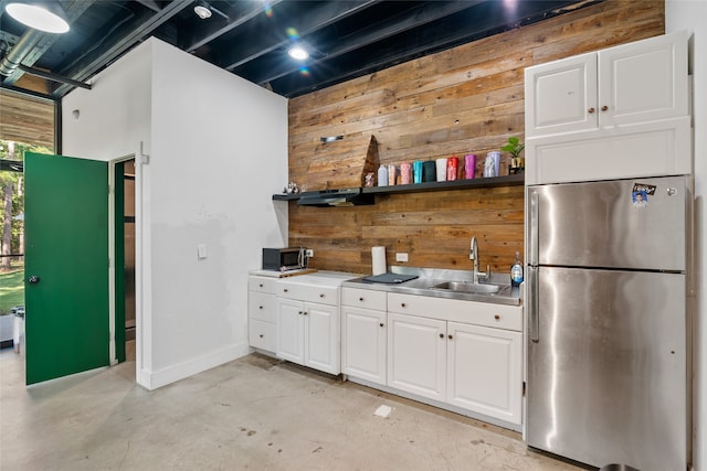 kitchen with wooden walls, white cabinetry, appliances with stainless steel finishes, and sink