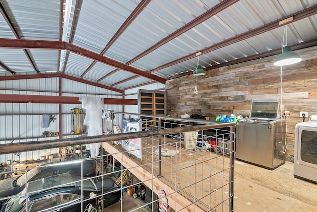 miscellaneous room with lofted ceiling, wooden walls, hardwood / wood-style floors, and washing machine and clothes dryer